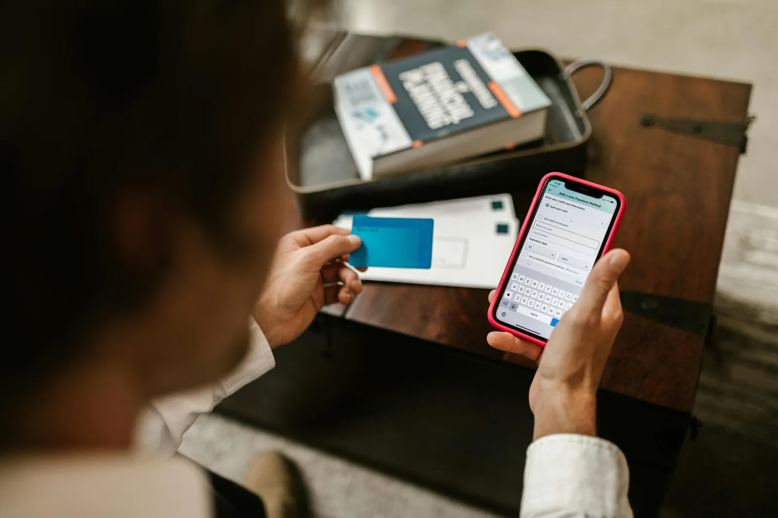 User completing an online payment on a smartphone while holding a card.